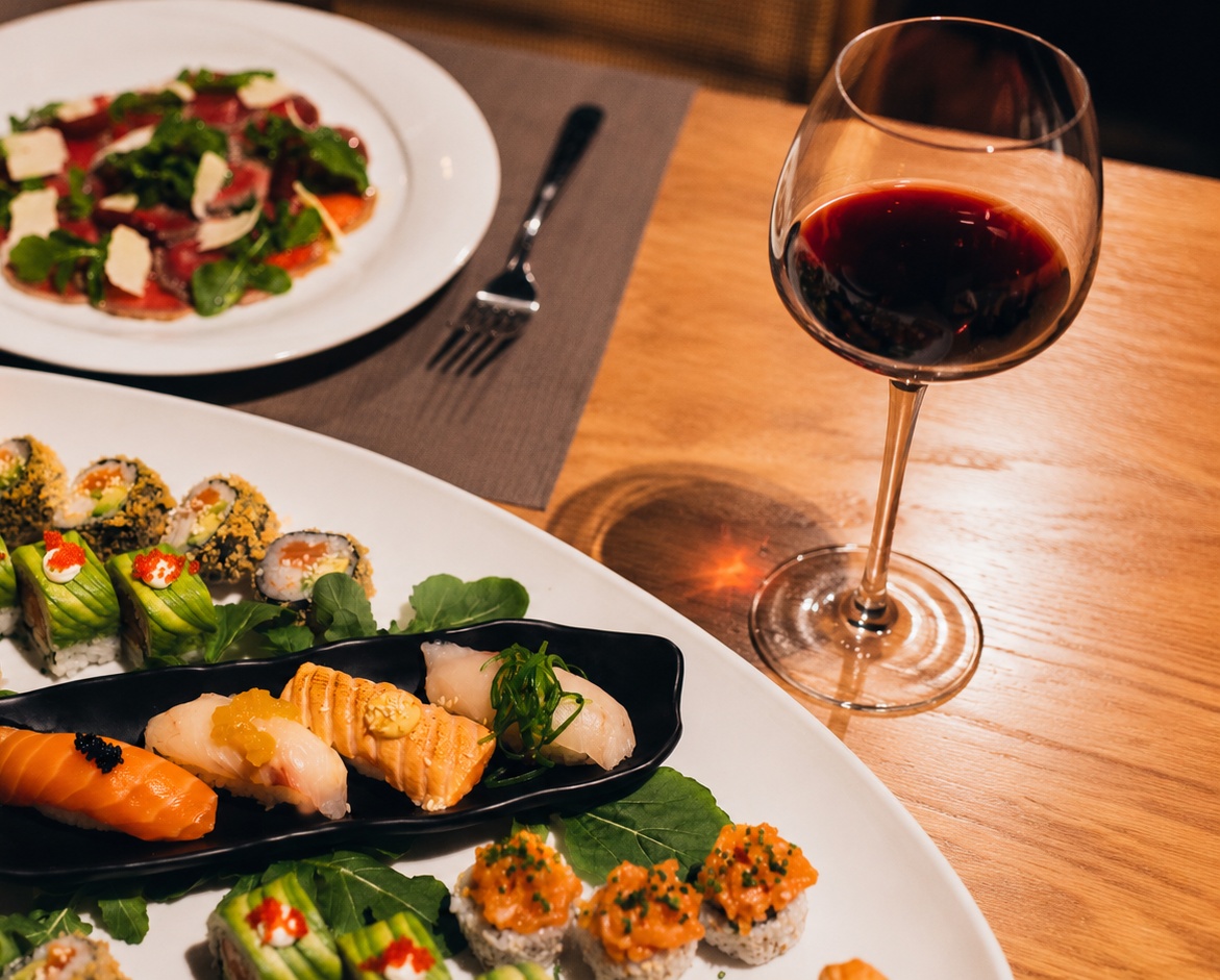 Glass of red wine with sushi platter