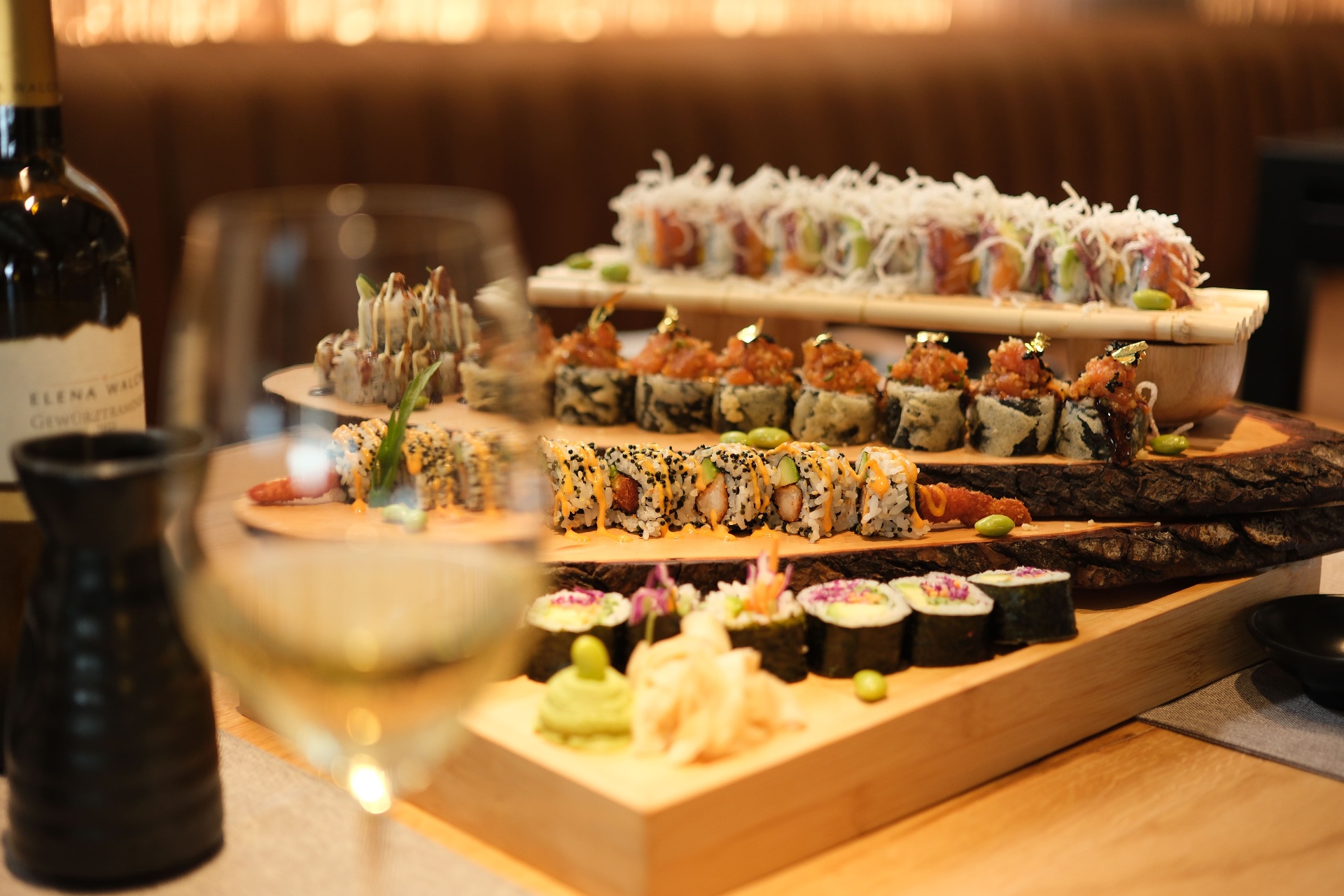 A glass of white wine alongside an Ujvara sushi platter